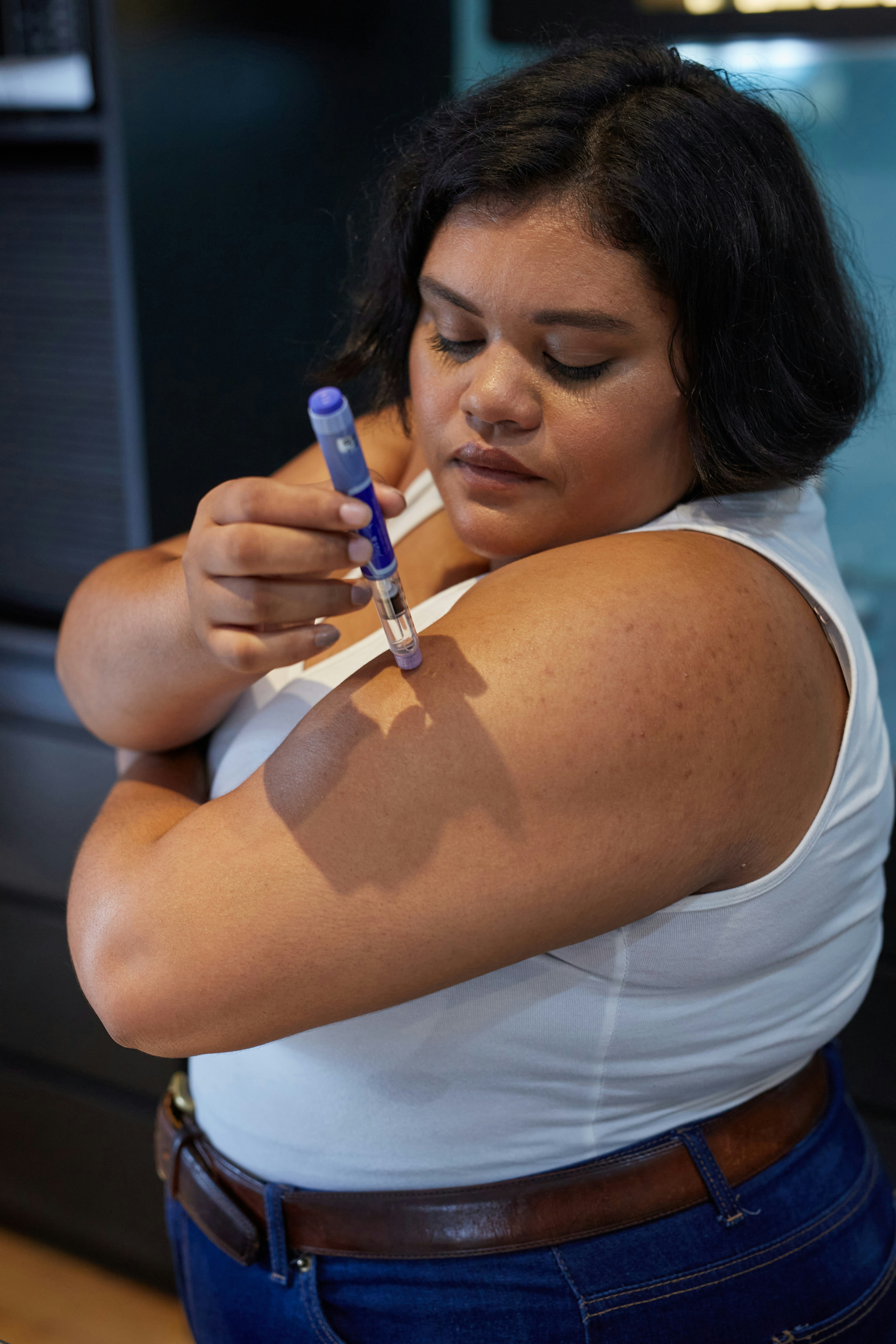 Woman self-injecting a GLP-1 medication pen
